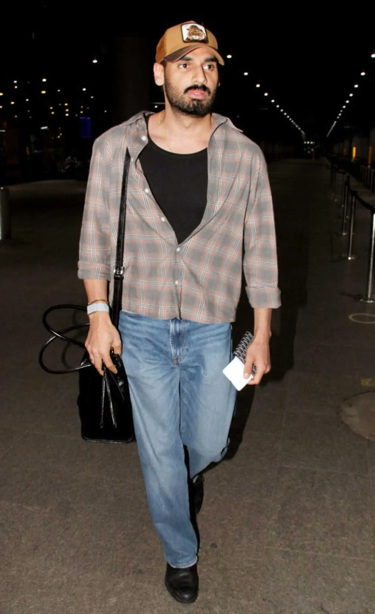 Ahan Shetty was seen arriving in the city on Sunday morning in a chequrred shirt worn over a black t-shirt, paired with denim pants and a cap.